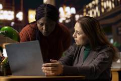 Mature students at a library desk studying materials on a laptop